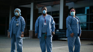 Three EVS workers wearing PPE and standing outside